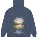 Navy blue Comfort Color hoodie sweatshirt with a meadow, pond and wildflowers with The Lord is my shepherd, I shall not want. He makes me lie down in green pastures. He leads me beside still waters. printed on it. Psalm 23:1-2