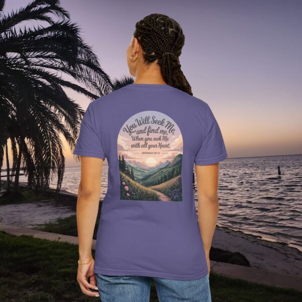 Purple Christian t-shirt with Jeremiah 29:13 scripture, mountain valley, and sunset graphic, worn by a person in a serene beach setting.