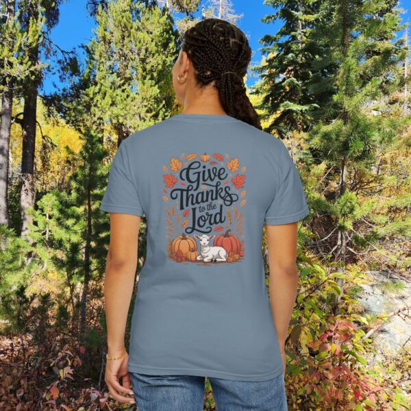 Model in a woods setting wearing a Blue Give Thanks to the Lord t-shirt with Thanksgiving design showing a lamb, pumpkins, and fall leaves.