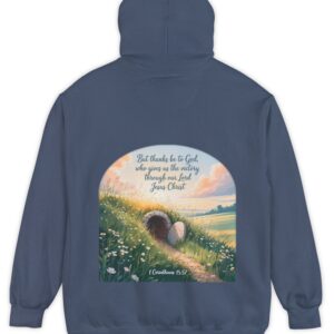 Navy blue Comfort Colors hoodie sweatshirt with a field and an open tomb with the rock rolled away. Printed on it is 1 Corinthians 15:57 But thanks be to God, who gives us the victory through our Lord Jesus Christ.