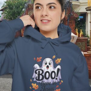 Model on a Halloween set wearing a Gray Boo! -lieve in Jesus Halloween Hoodie, design showing a cute ghost with fall leaves.