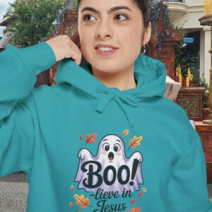 Model on a Halloween set wearing a Teal Boo! -lieve in Jesus Halloween Hoodie, design showing a cute ghost with fall leaves.