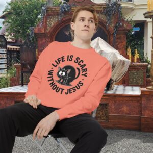Model on a Halloween set wearing a orange Life is Scary Without Jesus Halloween Sweatshirt, design showing a cute frightened black cat.
