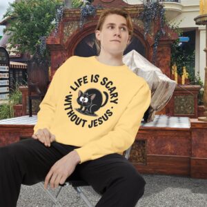 Model on a Halloween set wearing a yellow Life is Scary Without Jesus Halloween Sweatshirt, design showing a cute frightened black cat.