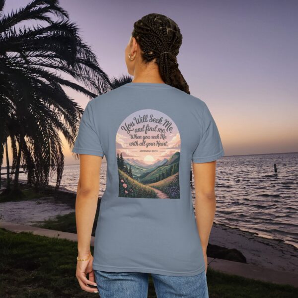 Blue Christian t-shirt with Jeremiah 29:13 scripture, mountain valley, and sunset graphic, worn by a person in a serene beach setting.