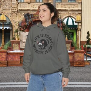 Model on a Halloween set wearing a gray Life is Scary Without Jesus Halloween Hoodie, design showing a cute frightened black cat.