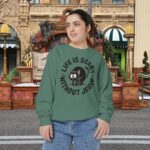 Model on a Halloween set wearing a green Life is Scary Without Jesus Halloween Sweatshirt, design showing a cute frightened black cat.