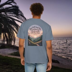 Blue Christian t-shirt with Jeremiah 29:13 scripture, mountain valley, and sunset graphic, worn by a person in a serene beach setting.