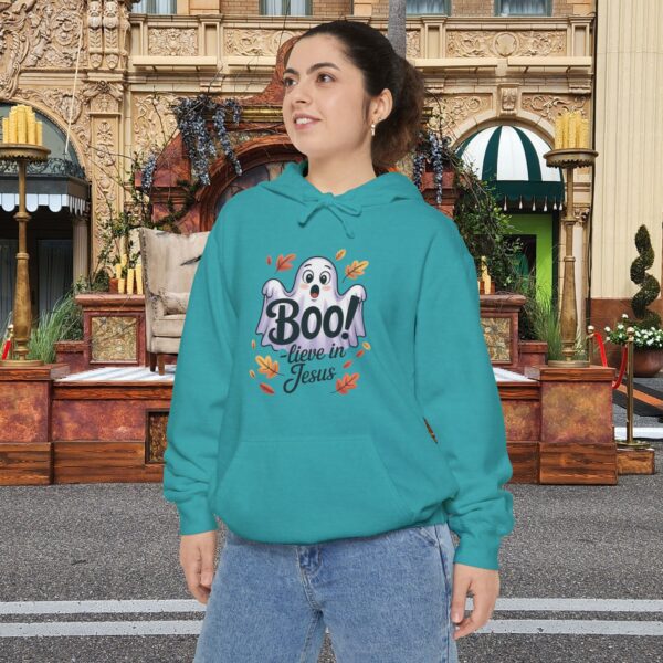 Model on a Halloween set wearing a Teal Boo! -lieve in Jesus Halloween Hoodie, design showing a cute ghost with fall leaves.