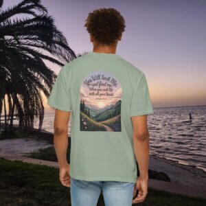 Green Christian t-shirt with Jeremiah 29:13 scripture, mountain valley, and sunset graphic, worn by a person in a serene beach setting.