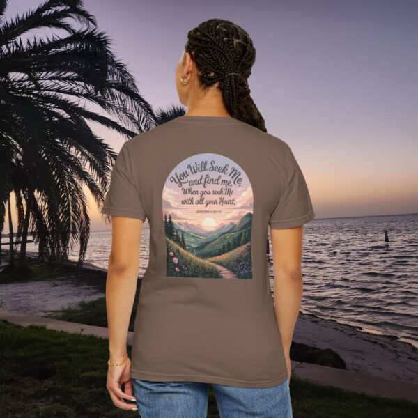 Brown Christian t-shirt with Jeremiah 29:13 scripture, mountain valley, and sunset graphic, worn by a person in a serene beach setting.