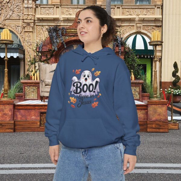 Model on a Halloween set wearing a blue Boo! -lieve in Jesus Halloween Hoodie, design showing a cute ghost with fall leaves.
