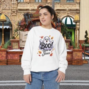 Model on a Halloween set wearing a white Boo! -lieve in Jesus Halloween Sweatshirt, design showing a cute ghost with fall leaves.