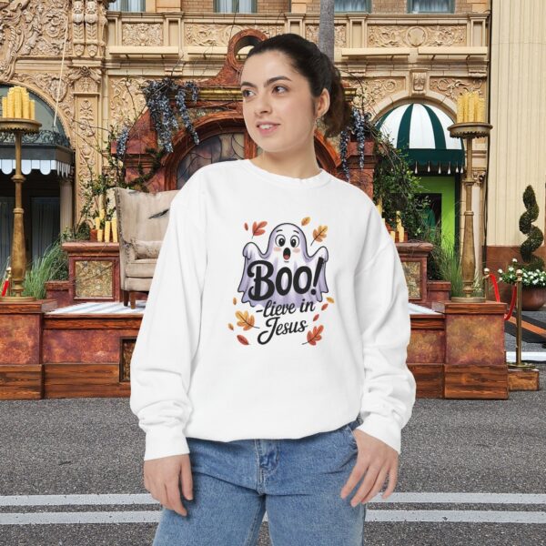 Model on a Halloween set wearing a white Boo! -lieve in Jesus Halloween Sweatshirt, design showing a cute ghost with fall leaves.
