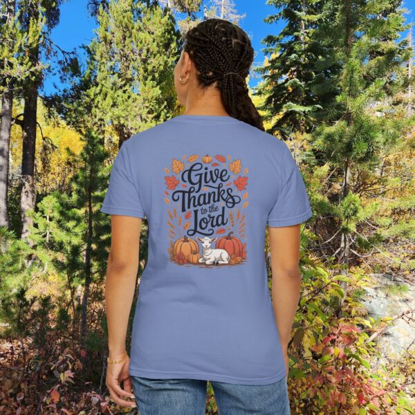 Model in a woods setting wearing a Blue Give Thanks to the Lord t-shirt with Thanksgiving design showing a lamb, pumpkins, and fall leaves.