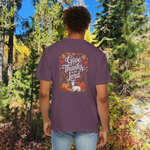 Model in a woods setting wearing a Purple Give Thanks to the Lord t-shirt with Thanksgiving design showing a lamb, pumpkins, and fall leaves.