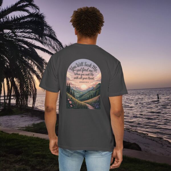 Gray Christian t-shirt with Jeremiah 29:13 scripture, mountain valley, and sunset graphic, worn by a person in a serene beach setting.