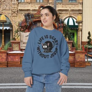 Model on a Halloween set wearing a blue Life is Scary Without Jesus Halloween Sweatshirt, design showing a cute frightened black cat.