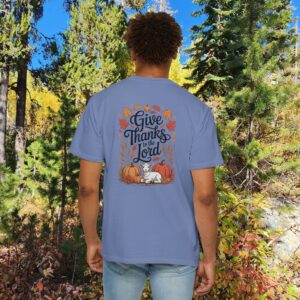 Model in a woods setting wearing a Blue Give Thanks to the Lord t-shirt with Thanksgiving design showing a lamb, pumpkins, and fall leaves.