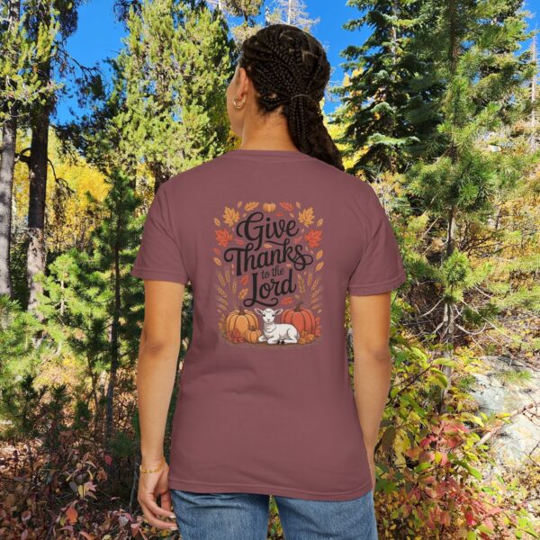 Model in a woods setting wearing a Maroon Give Thanks to the Lord t-shirt with Thanksgiving design showing a lamb, pumpkins, and fall leaves.