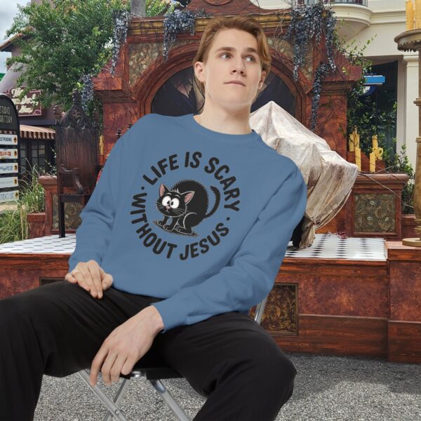 Model on a Halloween set wearing a blue Life is Scary Without Jesus Halloween Sweatshirt, design showing a cute frightened black cat.