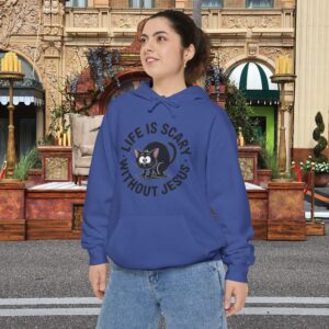 Model on a Halloween set wearing a blue Life is Scary Without Jesus Halloween Hoodie, design showing a cute frightened black cat.