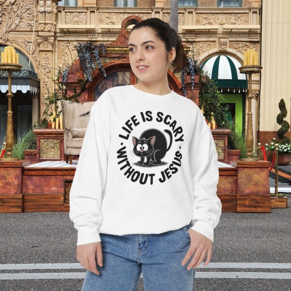 Model on a Halloween set wearing a white Life is Scary Without Jesus Halloween Sweatshirt, design showing a cute frightened black cat.