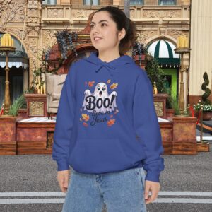 Model on a Halloween set wearing a Blue Boo! -lieve in Jesus Halloween Hoodie, design showing a cute ghost with fall leaves.