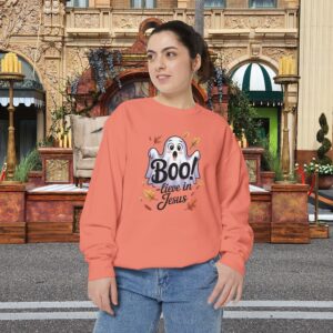 Model on a Halloween set wearing an Orange Boo! -lieve in Jesus Halloween Sweatshirt, design showing a cute ghost with fall leaves.