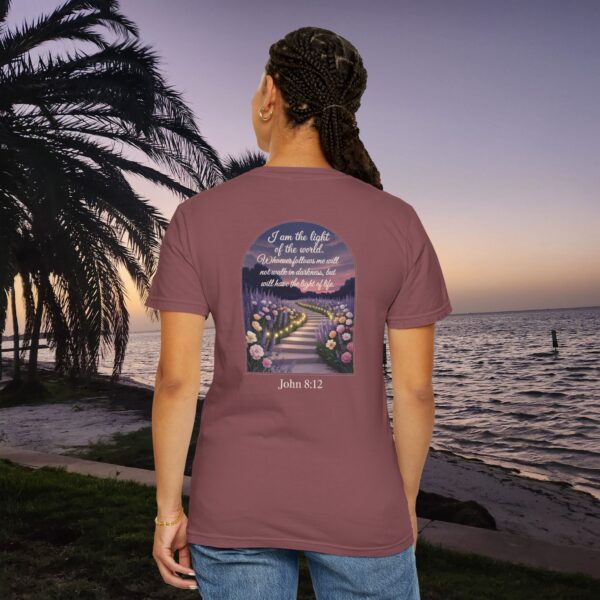 Maroon Christian t-shirt with John 8:12 scripture, lit stairway path with flowers and sunset design, worn by a person standing on a sunset beach.
