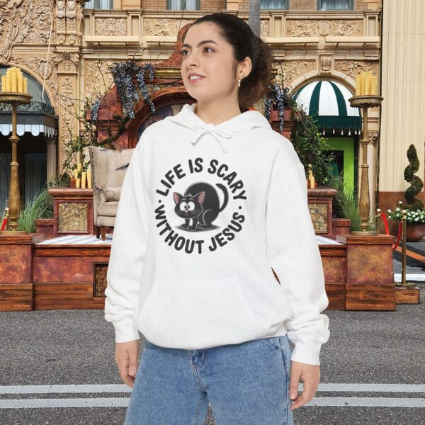 Model on a Halloween set wearing a white Life is Scary Without Jesus Halloween Hoodie, design showing a cute frightened black cat.