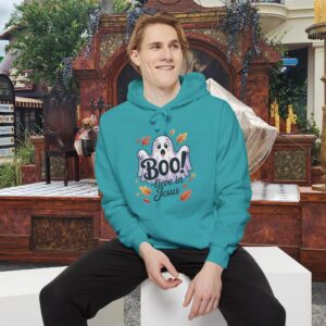 Model on a Halloween set wearing a Teal Boo! -lieve in Jesus Halloween Hoodie, design showing a cute ghost with fall leaves.