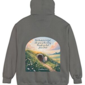 Grey Comfort Colors hoodie sweatshirt with a field and an open tomb with the rock rolled away. Printed on it is 1 Corinthians 15:57 But thanks be to God, who gives us the victory through our Lord Jesus Christ.