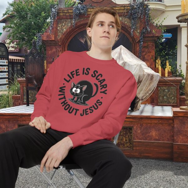 Model on a Halloween set wearing a Red Life is Scary Without Jesus Halloween Sweatshirt, design showing a cute frightened black cat.