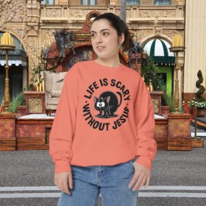 Model on a Halloween set wearing a orange Life is Scary Without Jesus Halloween Sweatshirt, design showing a cute frightened black cat.