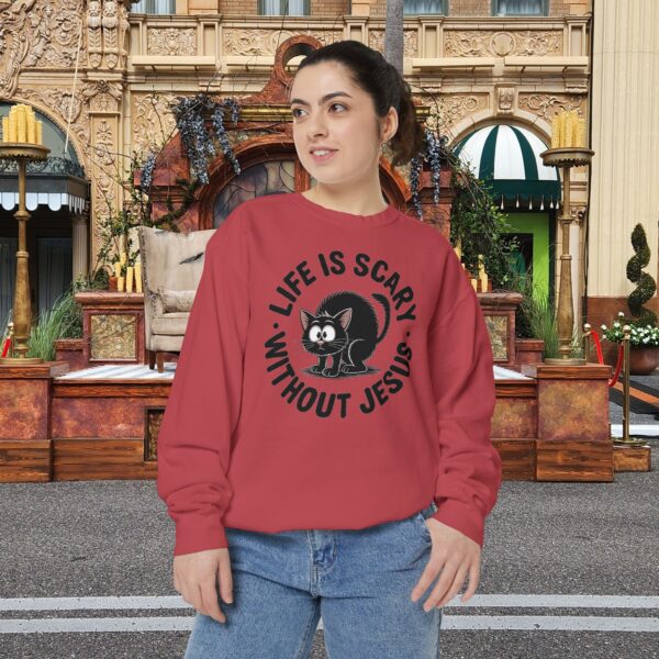 Model on a Halloween set wearing a Red Life is Scary Without Jesus Halloween Sweatshirt, design showing a cute frightened black cat.