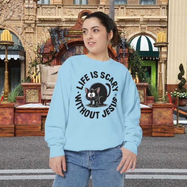 Model on a Halloween set wearing a blue Life is Scary Without Jesus Halloween Sweatshirt, design showing a cute frightened black cat.