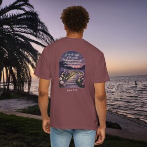 Maroon Christian t-shirt with John 8:12 scripture, lit stairway path with flowers and sunset design, worn by a person standing on a sunset beach.