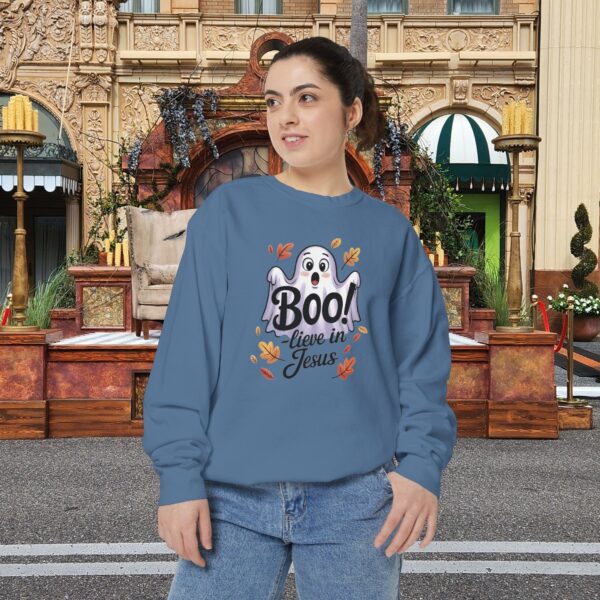 Model on a Halloween set wearing a Blue Boo! -lieve in Jesus Halloween Sweatshirt, design showing a cute ghost with fall leaves.