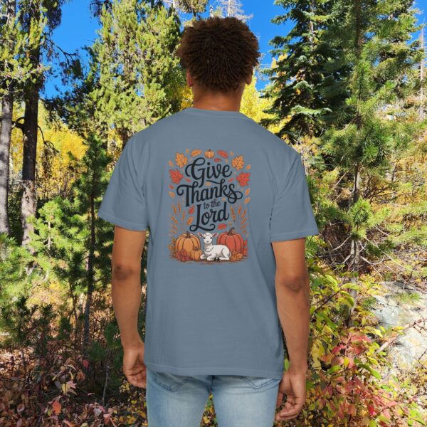 Model in a woods setting wearing a Blue Give Thanks to the Lord t-shirt with Thanksgiving design showing a lamb, pumpkins, and fall leaves.