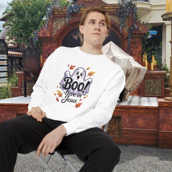 Model on a Halloween set wearing a white Boo! -lieve in Jesus Halloween Sweatshirt, design showing a cute ghost with fall leaves.