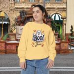 Model on a Halloween set wearing a Yellow Boo! -lieve in Jesus Halloween Sweatshirt, design showing a cute ghost with fall leaves.