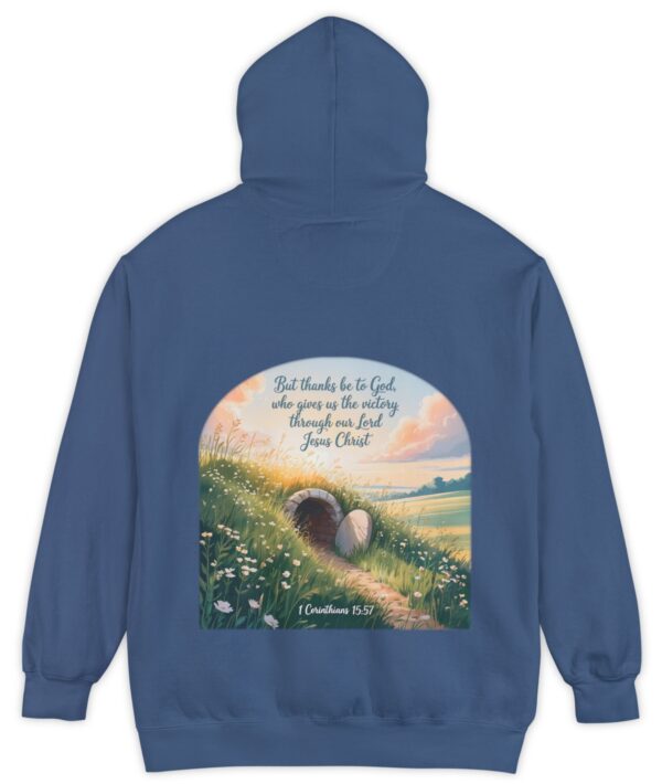 Blue Comfort Colors hoodie sweatshirt with a field and an open tomb with the rock rolled away. Printed on it is 1 Corinthians 15:57 But thanks be to God, who gives us the victory through our Lord Jesus Christ.