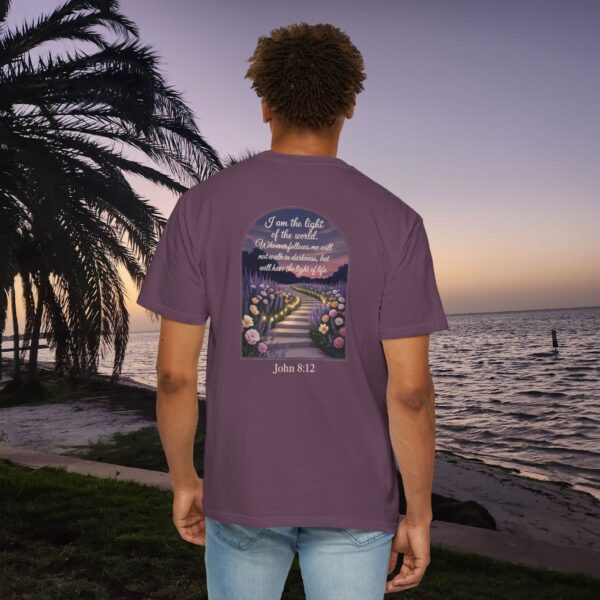Purple Christian t-shirt with John 8:12 scripture, lit stairway path with flowers and sunset design, worn by a person standing on a sunset beach.