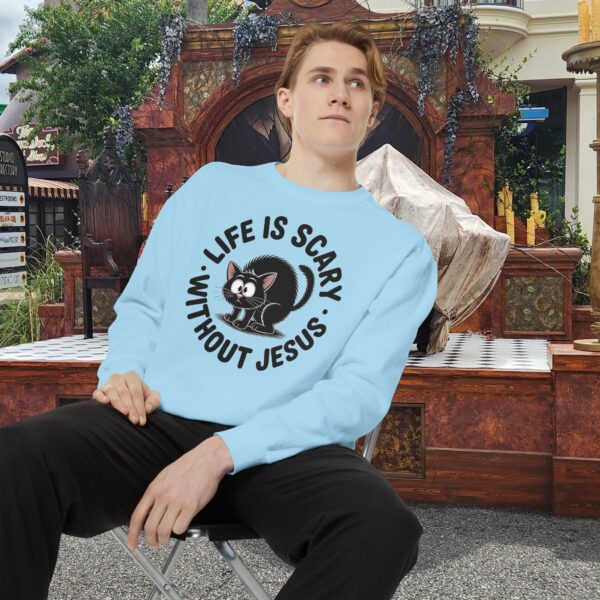 Model on a Halloween set wearing a blue Life is Scary Without Jesus Halloween Sweatshirt, design showing a cute frightened black cat.