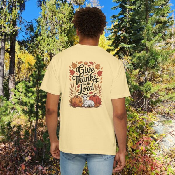 Model in a woods setting wearing a Yellow Give Thanks to the Lord t-shirt with Thanksgiving design showing a lamb, pumpkins, and fall leaves.