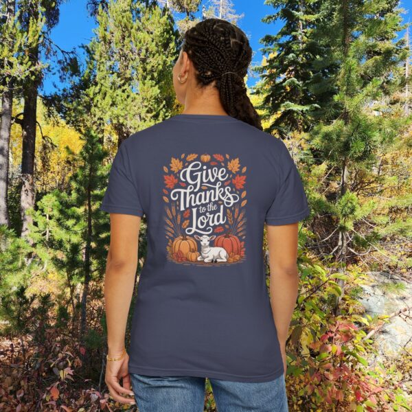 Model in a woods setting wearing a Gray Give Thanks to the Lord t-shirt with Thanksgiving design showing a lamb, pumpkins, and fall leaves.
