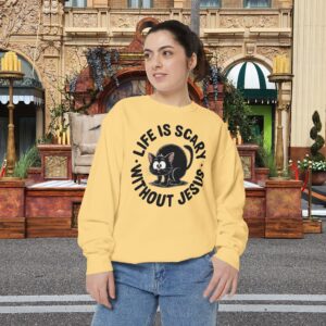 Model on a Halloween set wearing a yellow Life is Scary Without Jesus Halloween Sweatshirt, design showing a cute frightened black cat.