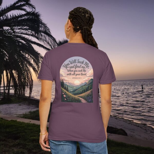Purple Christian t-shirt with Jeremiah 29:13 scripture, mountain valley, and sunset graphic, worn by a person in a serene beach setting.