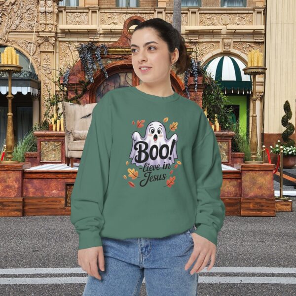 Model on a Halloween set wearing a Green Boo! -lieve in Jesus Halloween Sweatshirt, design showing a cute ghost with fall leaves.